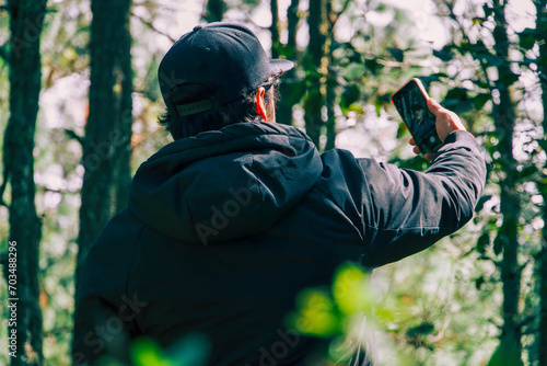 Persona sosteniendo un teléfono en un entorno de bosque. Conectando con la naturaleza y la tecnología