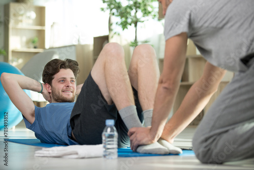 young man practising yoga with experienced trainer photo
