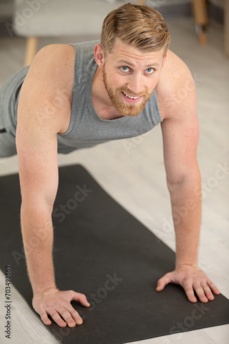 portrait of a sporty smiling young man doing push ups