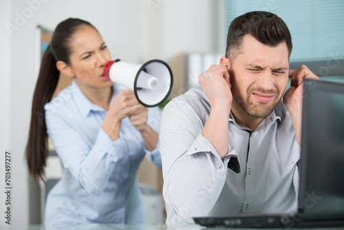 Fotografija woman shouting through megaphone at male colleague in office