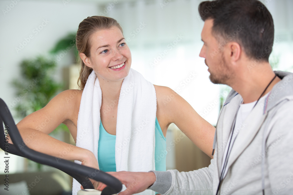 Fototapeta premium personal trainer advising woman using fitness equipment