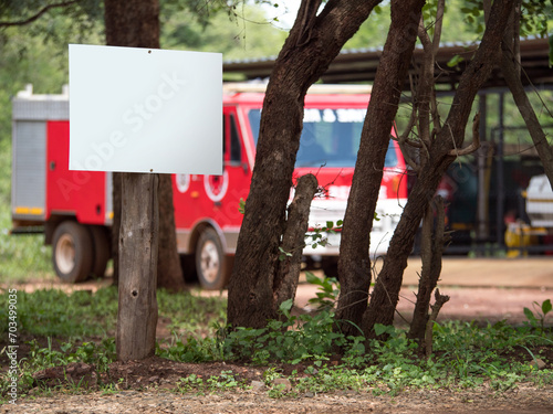 Cuadro en lienzo Panneau blanc sur un poteau en bois avec des arbres et un camion de pompier en a