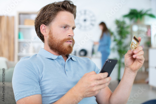 man with serious expression holding smartphone and credit card