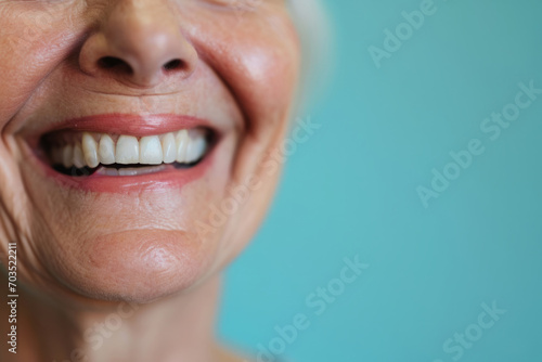Smiling elderly person with smooth white teeth implants. Close up portrait of female mouth on pastel blue background, banner with copy space. Positive senior woman