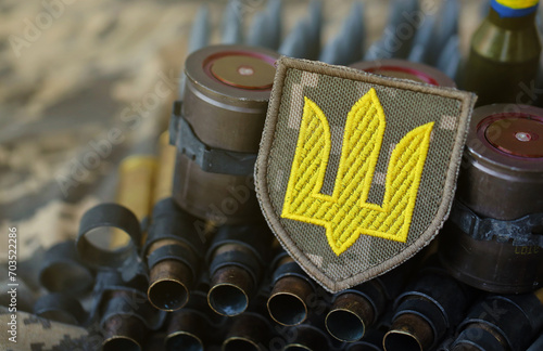 Ukrainian army symbol on machine gun belt lies on ukrainian pixeled military camouflage close up photo