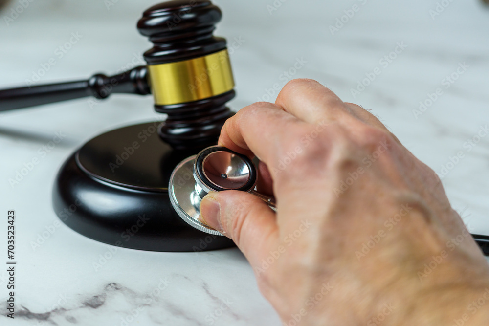 The Intersection of Law and Healthcare. A Close-Up Image of a Judge’s Hand Holding a Stethoscope Next to a Gavel on a Marble Surface. Perfect for Legal and Medical Professional Themes