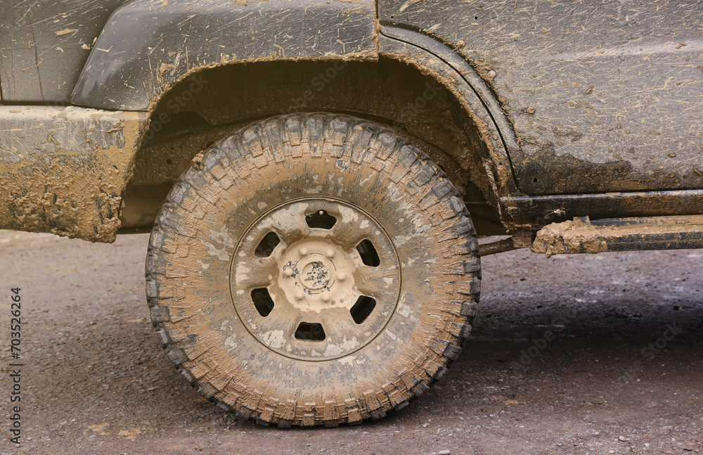 Wheel closeup in a countryside landscape with a mud road. Off-road 4x4 suv automobile with ditry body after drive in muddy road area Wheel closeup in a countryside landscape with a mud road. Off-road 4x4 suv automobile with ditry body after drive in muddy road area
