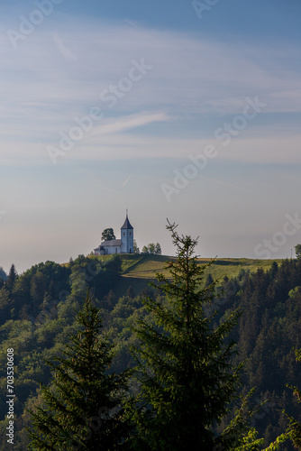 Church of Saint Primoz in Jamnik village  Slovenia  Europe. The church is on the ridge of the mountains. Sunrise  mountain peaks in the background.