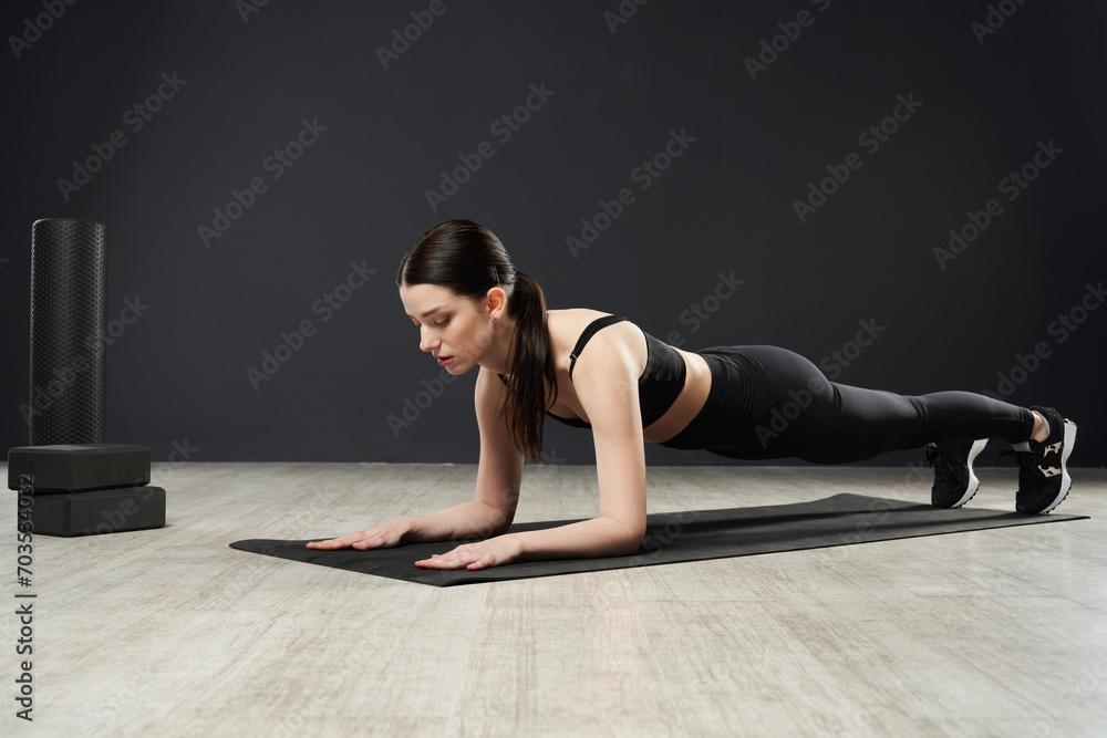 Brunette sportswoman standing in plank position on yoga mat, while training hard in gym. Side view of determined caucasian girl in activewear keeping body in tense, doing plank. Concept of sport. Brunette sportswoman standing in plank position on yoga mat, while training hard in gym. Side view of determined caucasian girl in activewear keeping body in tense, doing plank. Concept of sport.