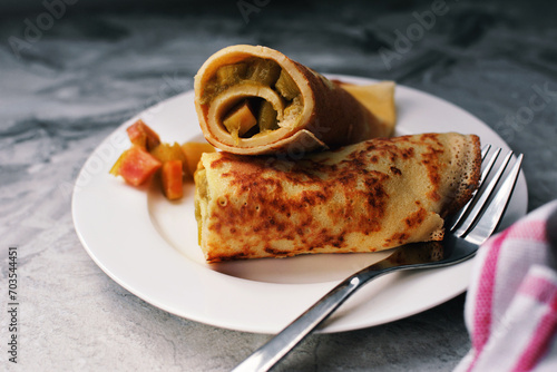 Rolled crepes or balkan pancakes stuffed caramelized rhubarb cubes