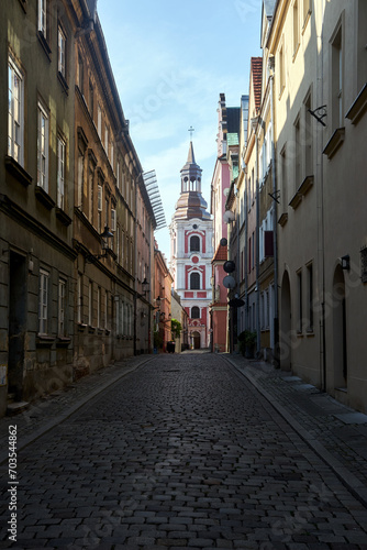 Fototapeta Naklejka Na Ścianę i Meble -  Cobbled street and historic belfry of a baroque church in the city of Poznan