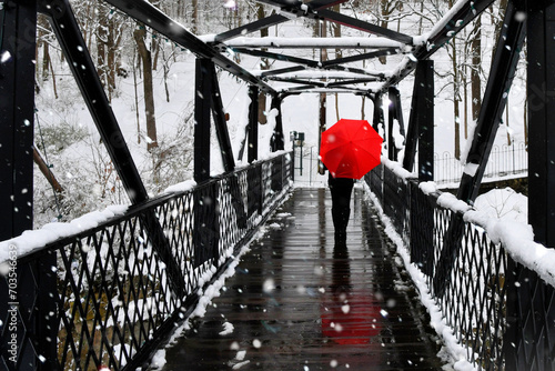 Woman with red umbrella walking across Sears Hill Bridge in downtown Staunton VA in snow after winter snowstorm photo