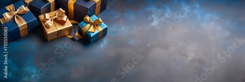 Blue and gold gift box with elegant gold ribbon on dark blue dreamy background. Greeting present with copy space for Christmas present, valentine or birthday photo