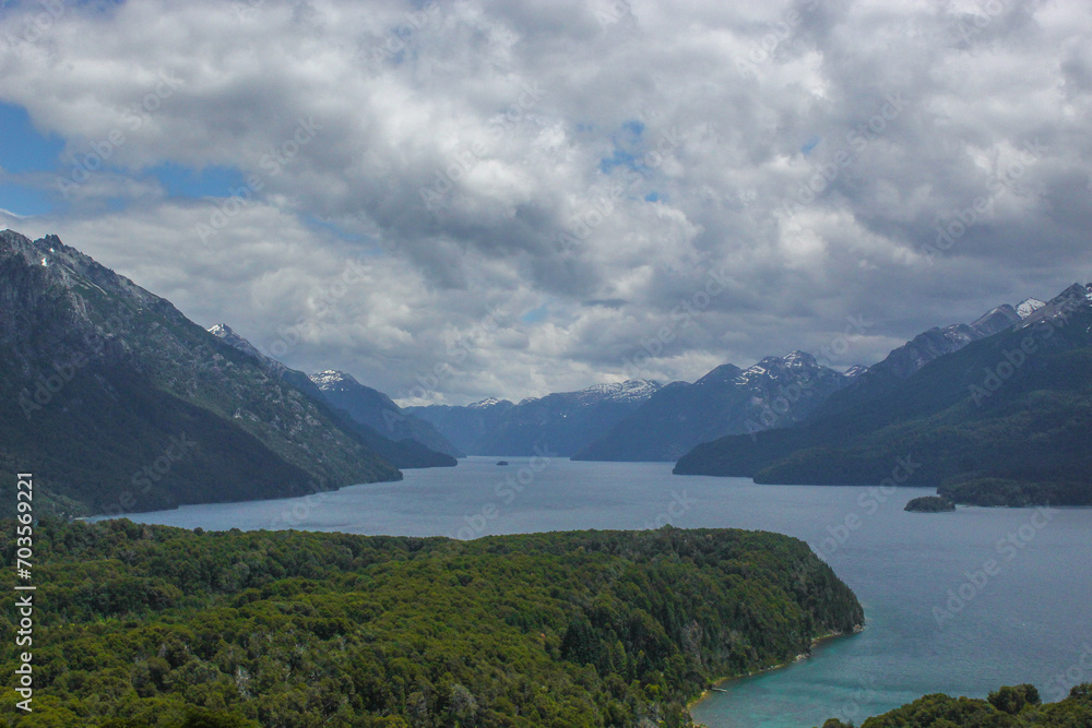 Mountain range covered by forest and separated by Nahuel Huapi Lake on a very cloudy day.