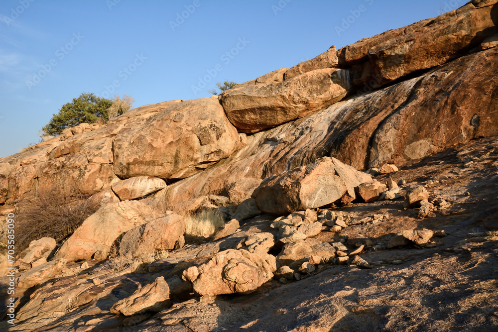 Large boulders are scattered along the rocky mountain slope. Blue sky above Large boulders are scattered along the rocky mountain slope. Blue sky above