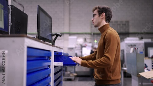 Video of an engineer using computer to change the inventory picking up a piece of metal in a cnc modern factory photo