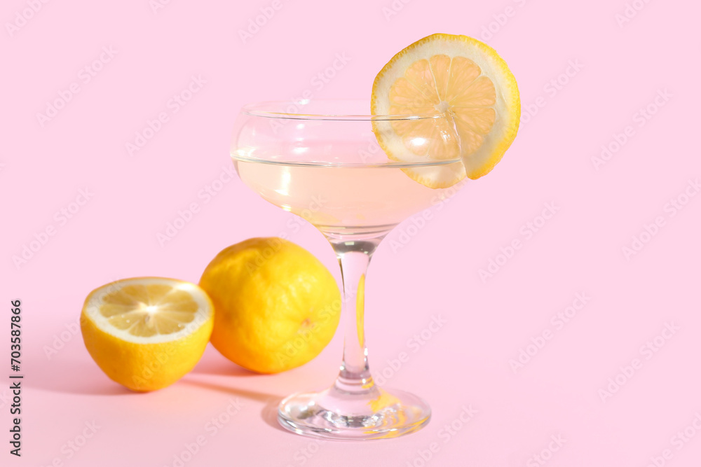 Glass of tasty martini and lemon on pink background