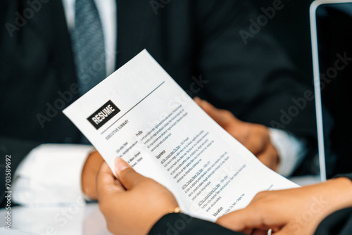 Human resources department manager reads CV resume document of an employee candidate at interview room. Job application, recruit and labor hiring concept. uds photo
