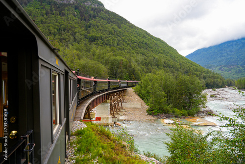 Narrow-gauge train of the White Pass and Yukon Route on an old trestles bridge in the Alaskan mountains between Skagway and Canada