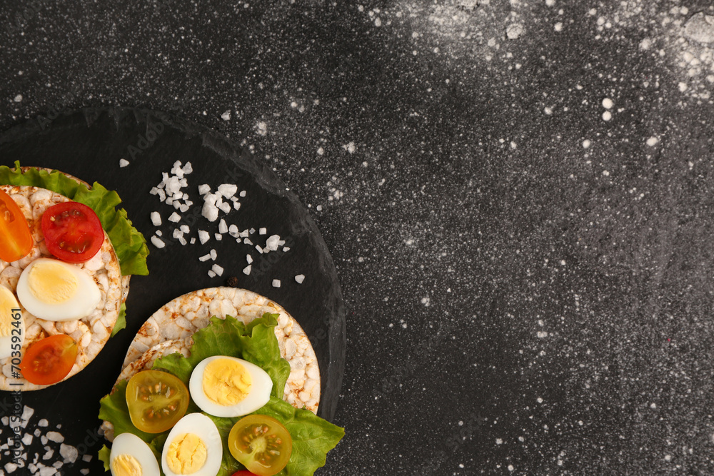 Rice crackers with quail eggs, tomatoes and lettuce on dark grunge background Rice crackers with quail eggs, tomatoes and lettuce on dark grunge background