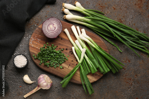 Board with slices of fresh scallion and onion on dark background photo