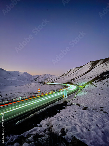 Enchanting allure of Lindis Pass at sunset. Capturing the magic of long exposure, witness mesmerizing light trails along the scenic highway in South Island, New Zealand. A journey through time.