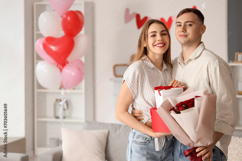 Beautiful young couple with bouquet of flowers and gift boxes celebrating Valentine's Day at home Beautiful young couple with bouquet of flowers and gift boxes celebrating Valentine's Day at home