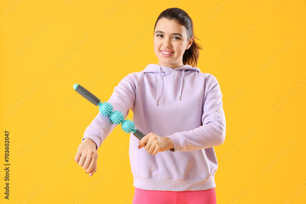 Young woman with massage roller on yellow background Young woman with massage roller on yellow background