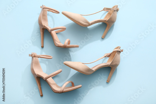 Stylish nude high-heeled shoes on color background