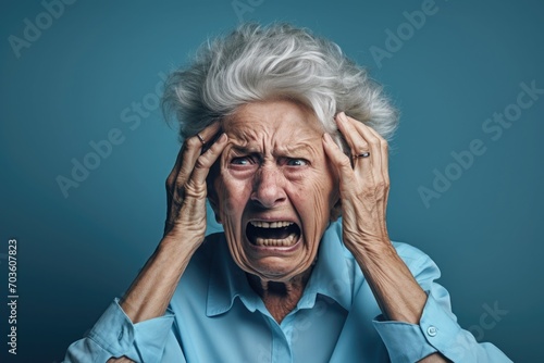 Upset old, adult woman, female in blue t shirt screaming and crying with opened mouth and closed eyes against