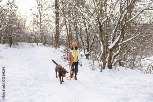 Woman walking with adorable Labrador Retriever dog in snowy park © New Africa