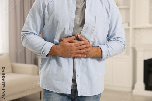 Young man suffering from stomach pain indoors, closeup