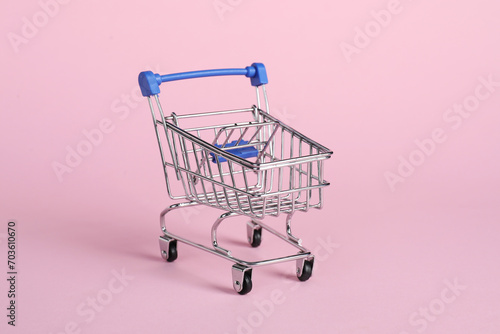 Small metal shopping cart on pink background