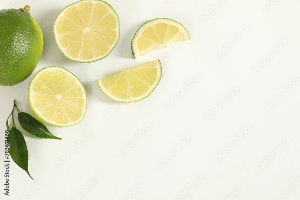 Fresh limes and green leaves on white background, flat lay. Space for text Fresh limes and green leaves on white background, flat lay. Space for text