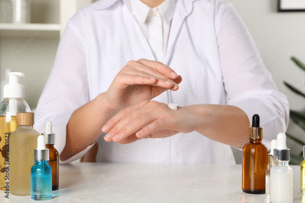 Dermatologist testing cosmetic product at white table indoors, closeup Dermatologist testing cosmetic product at white table indoors, closeup