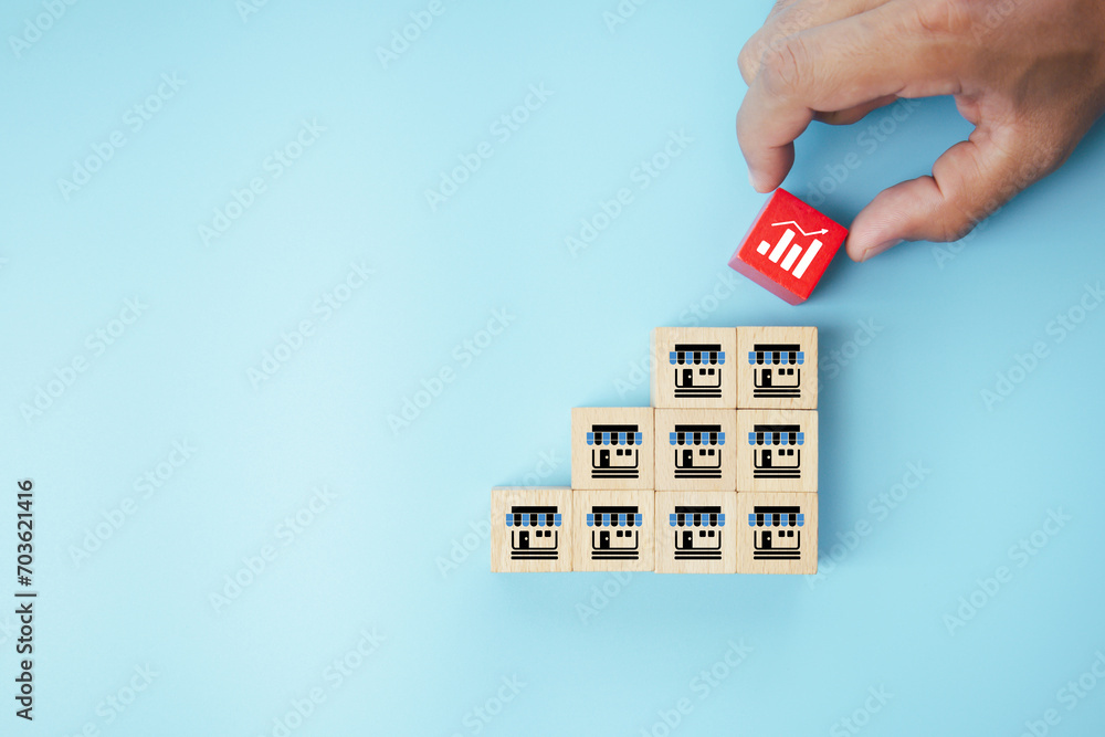 Hand choose franchise or franchising business store icon on cube wooden block stack pyramid for strategy organization company growth branch expand marketing management and investment plan - obrazy, fototapety, plakaty 