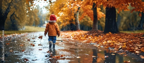 Child in autumn park playing in the rain.