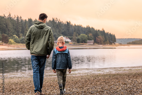 Father and son walking talking by a lake spending time together bonding in nature 