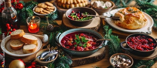 Classic Polish Christmas Eve dishes on festive table- beet soup with dumplings, sauerkraut with mushrooms, cranberry spread, pastries, salad, and herrings.