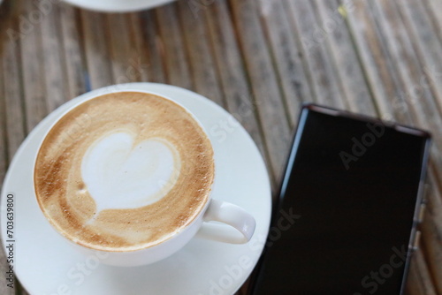 Hot latte in a white glass on a bamboo table