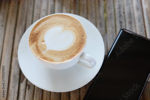 Hot latte in a white glass on a bamboo table