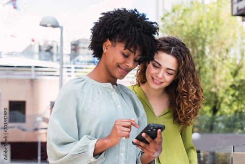Reaching out to new networks. Shot of two businesswomen looking at something on a cellphone in the city.