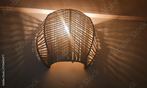The image is a still life photograph of a lamp casting light and shadow on the ground in a dark environment.