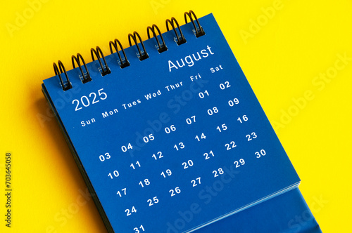 August 2025 blue desk calendar on yellow cover background.