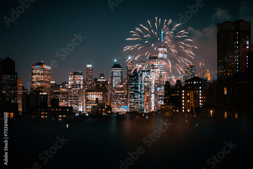 View of financial district Manhattan buildings and lights at night with fireworks at the sky