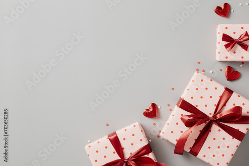 Valentine's Day background with gift boxes and heart candy on gray table. Love, romantic flat lay composition. Top view.