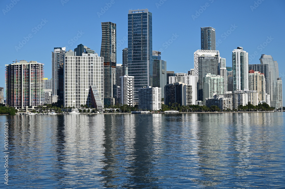 City of Miami, Florida skyline reflected in calm water of Biscayne Bay on calm cloudless December morning.