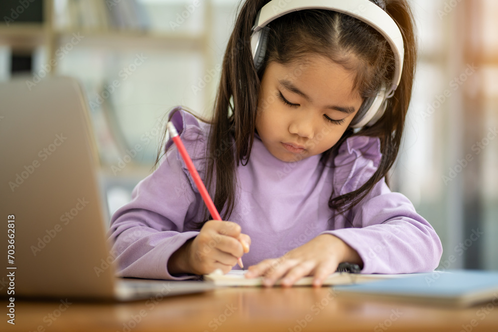 Young Asian female student wearing headphones studying watching video conference, laptop computer, online distance learning at home Young Asian female student wearing headphones studying watching video conference, laptop computer, online distance learning at home