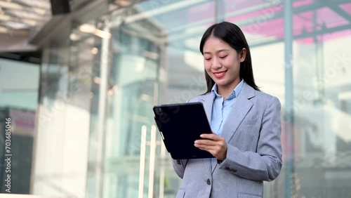 Young Asian business woman leader entrepreneur, professional manager holding digital tablet computer uon the street in big city photo