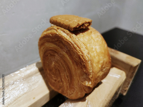 Cromboloni, New York Roll Croissant with biscoff topping, served on a wooden stand photo